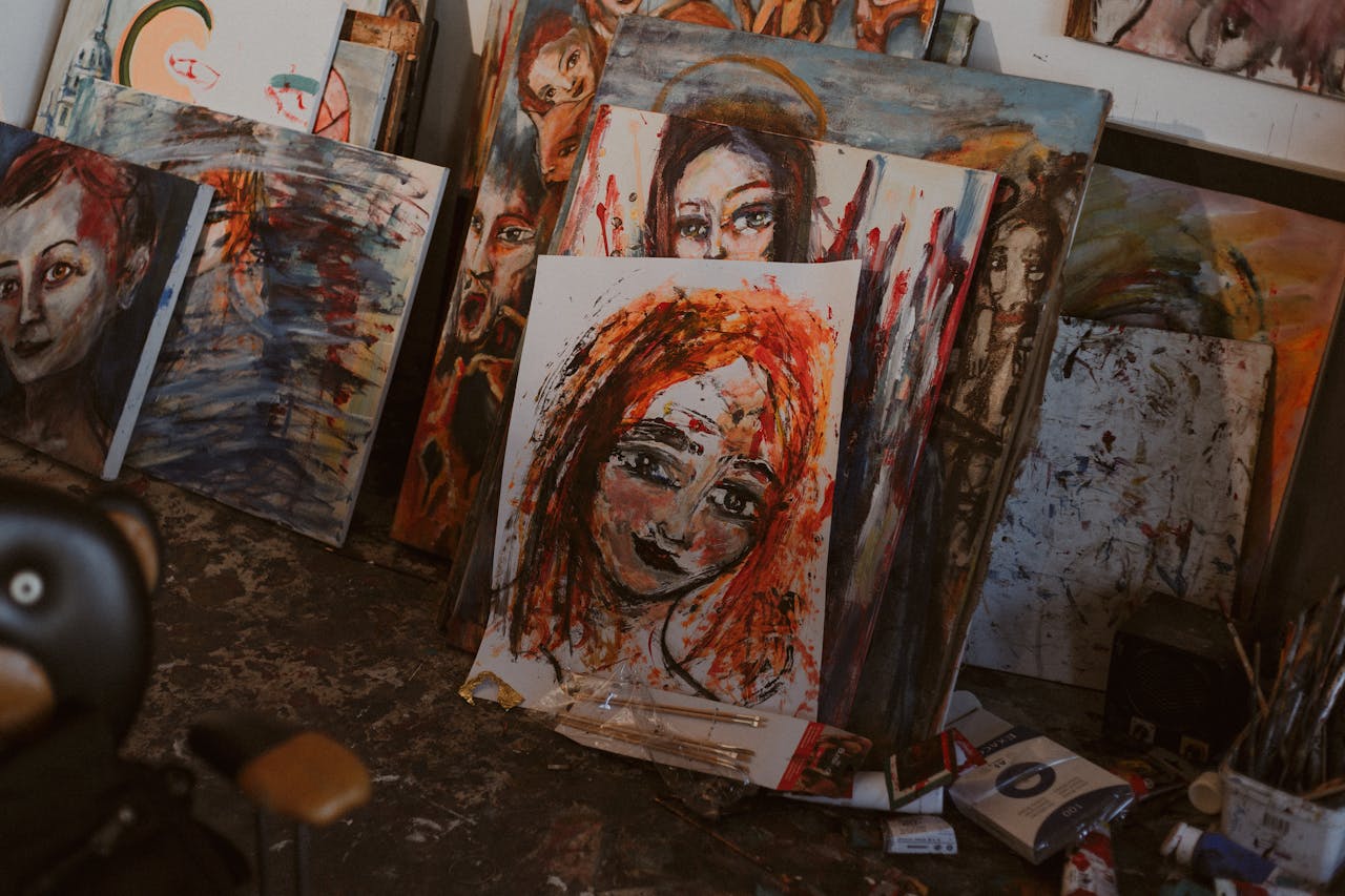 A creative art studio with colorful paintings of diverse female faces on canvases.